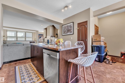 Kitchen island with a built-in stainless steel dishwasher, an undermount sink, and a granite-finish countertop - 621 Mcdonough Link Link, Edmonton, AB 