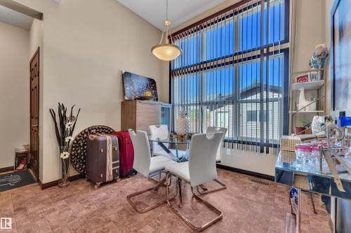 Dining area featuring a soaring ceiling, a full-height window with vertical blinds, and tile flooring - 621 Mcdonough Link Link, Edmonton, AB 