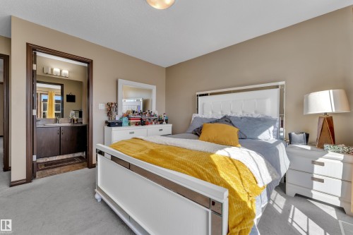 Carpeted room with a doorway revealing a vanity with a dark wood-finish cabinet and a rectangular sink - 621 Mcdonough Link Link, Edmonton, AB 