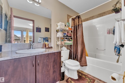 Bathroom featuring a wood-finish vanity with a single basin sink and a large wall-mounted mirror - 621 Mcdonough Link Link, Edmonton, AB 