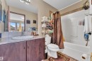 Bathroom featuring a wood-finish vanity with a single basin sink and a large wall-mounted mirror - 621 Mcdonough Link Link, Edmonton, AB 