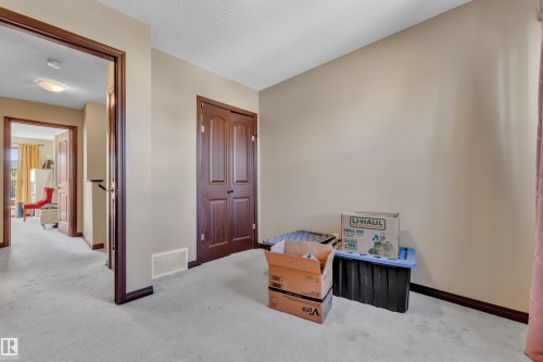 Carpeted room featuring a double-door closet, neutral wall paint, and dark wood trim - 621 Mcdonough Link Link, Edmonton, AB 