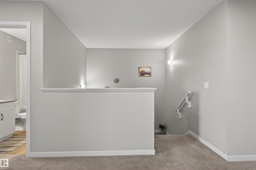 Upper-level landing featuring textured carpeting, neutral wall finishes, and white baseboards - 22638 99A Avenue, Edmonton, AB 