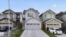Modern multi-story home featuring light gray vertical and horizontal siding, a two-car garage with a concrete driveway, and a gabled roofline - 22638 99A Avenue, Edmonton, AB 