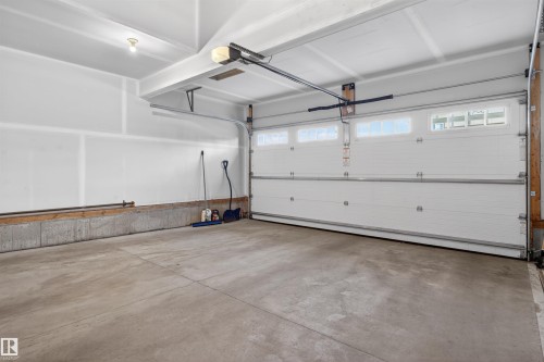Spacious garage featuring a concrete floor, white interior walls, and a white overhead door with transom windows - 22638 99A Avenue, Edmonton, AB 