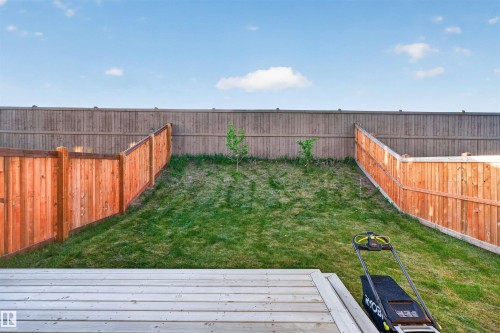 Expansive backyard featuring a wood-plank deck, sloped lawn, and perimeter wood fencing - 22638 99A Avenue, Edmonton, AB 