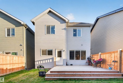 Rear exterior featuring light grey siding, a two-tier wood deck, and a fenced yard with natural grass - 22638 99A Avenue, Edmonton, AB 