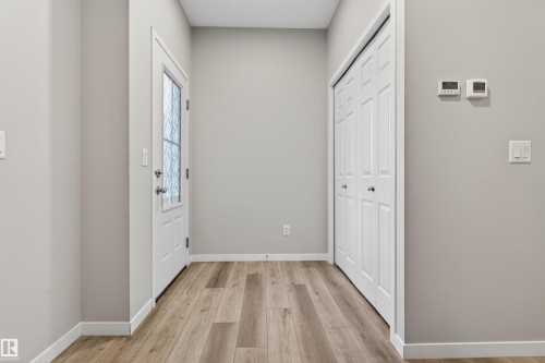 Entryway featuring wood-finish flooring, a white door with decorative glass, and a closet with bifold doors - 22638 99A Avenue, Edmonton, AB 