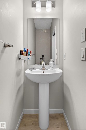 Pedestal sink with a polished chrome faucet, rectangular wall mirror, and brushed nickel two-light vanity fixture - 22638 99A Avenue, Edmonton, AB 