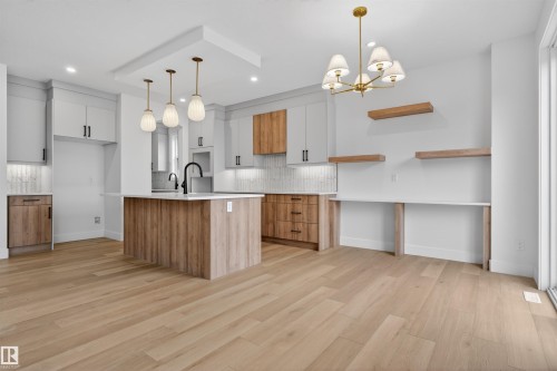 Open-concept kitchen featuring light wood-finish flooring, a central island with a solid surface countertop, and mixed-material cabinetry - 15 Redbud Way, St. Albert, AB - Indoor Photo Showing Kitchen With Upgraded Kitchen
