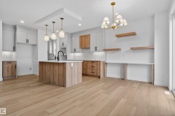 Open-concept kitchen featuring light wood-finish flooring, a central island with a solid surface countertop, and mixed-material cabinetry - 