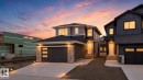 Modern two-story home featuring a dark gray exterior, a stone facade, and a contemporary garage door with frosted panels - 15 Redbud Way, St. Albert, AB  - Outdoor With Facade 