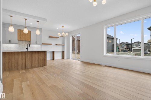 Open concept living area featuring light wood-finish flooring, a large picture window, and a sliding glass door - 15 Redbud Way, St. Albert, AB - Indoor Photo Showing Kitchen