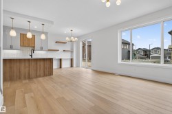 Open concept living area featuring light wood-finish flooring, a large picture window, and a sliding glass door - 