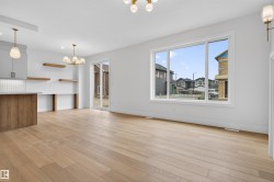 Spacious living area featuring light wood-finish flooring and ample natural light through a large picture window - 