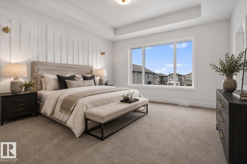 Spacious bedroom featuring light-colored carpeting, a large multi-pane window, and a tray ceiling - 15 Redbud Way, St. Albert, AB - Indoor Photo Showing Bedroom