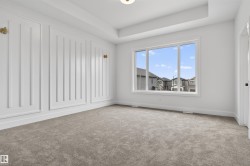 Spacious room with plush gray carpeting, tray ceiling, and a large multi-pane window - 