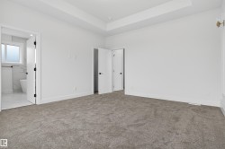 Spacious room featuring neutral carpeting, crisp white walls, and a recessed ceiling detail - 