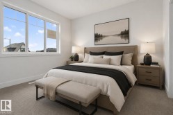 Spacious bedroom featuring light neutral wall paint, a large triple-pane window, and plush carpet flooring - 