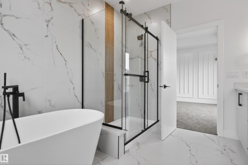 Freestanding soaking tub with matte black floor-mounted faucet, framed glass shower enclosure, and large format marble-look wall and floor tile - 15 Redbud Way, St. Albert, AB - Indoor Photo Showing Bathroom