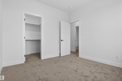 Interior room featuring light gray carpet, white walls, white trim, and a white interior door with black hardware - 15 Redbud Way, St. Albert, AB - Indoor Photo Showing Other Room