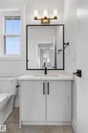 Bathroom vanity with white cabinetry, a white countertop, and a rectangular undermount sink with a matte black faucet - 