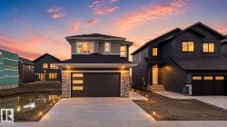 Contemporary two-story residence featuring a stone and siding exterior, an integrated garage with modern window inserts, and an illuminated concrete driveway - 