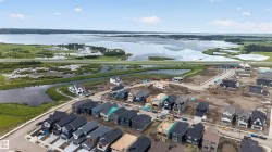 Developed residential area with varied home exteriors, featuring a substantial body of water and wetland areas in the background - 