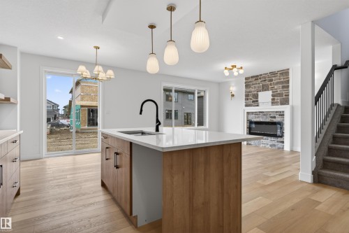 Kitchen island with white countertop and integrated sink, featuring a matte black faucet - 15 Redbud Way, St. Albert, AB - Indoor Photo Showing Kitchen With Fireplace With Upgraded Kitchen