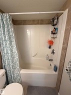 Bathtub and shower combination unit featuring a built-in soap dish and an integrated grab bar - 