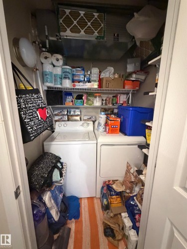 Dedicated laundry closet featuring a top-load washing machine and front-load dryer - 317 6921 199 Street, Edmonton, AB 