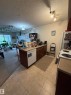 Kitchen area featuring warm-toned tile flooring, wood-finish cabinetry, a stainless steel sink, a built-in dishwasher, and a white electric range - 317 6921 199 Street, Edmonton, AB 