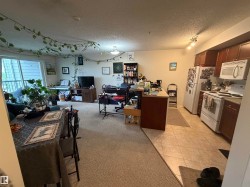 Open-concept living space featuring a kitchen with wood-finish cabinetry, white appliances, and tiled flooring - 