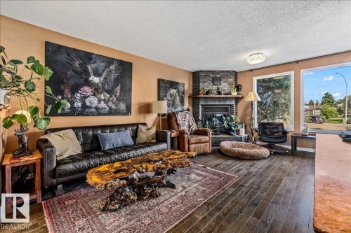 Living area featuring wood-finish flooring and a corner brick fireplace - 135 Homestead Crescent Nw, Edmonton, AB 