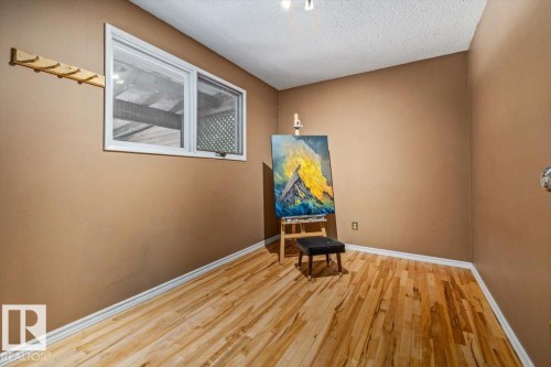 Wood-finish flooring with white baseboards, a single window with white trim, and a wall-mounted wooden coat rack - 135 Homestead Crescent Nw, Edmonton, AB 