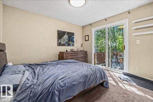 Bedroom featuring a sliding glass door leading to an outdoor deck, a built-in ceiling light fixture, and neutral-toned wall paint - 135 Homestead Crescent Nw, Edmonton, AB 