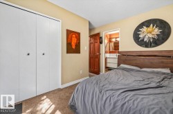 Carpeted room featuring a double bi-fold closet, a warm wood-panel door, and a built-in vanity with a mirror in the background - 