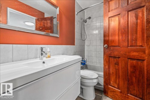 Bathroom featuring a white vanity with integrated sink, chrome faucet, and a large wall-mounted mirror - 135 Homestead Crescent Nw, Edmonton, AB 