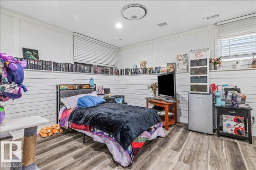 Room with wood-finish flooring, horizontal paneling on lower walls, and a window with horizontal blinds - 135 Homestead Crescent Nw, Edmonton, AB 