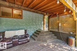 Covered patio featuring wood-finish decking, a multi-tiered staircase, and an exposed beam ceiling - 