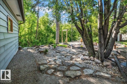Expansive exterior space featuring natural stone pathways, a gravel perimeter, and mature trees providing natural screening - 135 Homestead Crescent Nw, Edmonton, AB 