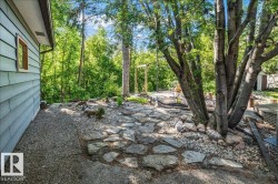 Expansive exterior space featuring natural stone pathways, a gravel perimeter, and mature trees providing natural screening - 