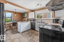 Kitchen featuring neutral-toned tile flooring, white cabinetry, a built-in dishwasher, a stainless steel sink, and a range hood - 135 Homestead Crescent Nw, Edmonton, AB 