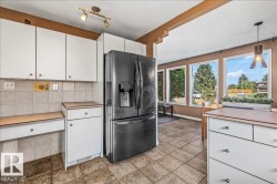 Kitchen area featuring white cabinetry, tile flooring, and a black refrigerator - 