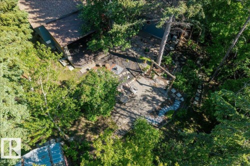 Outdoor entertaining area featuring a stone patio with a fire pit, surrounded by lush mature trees - 135 Homestead Crescent Nw, Edmonton, AB 