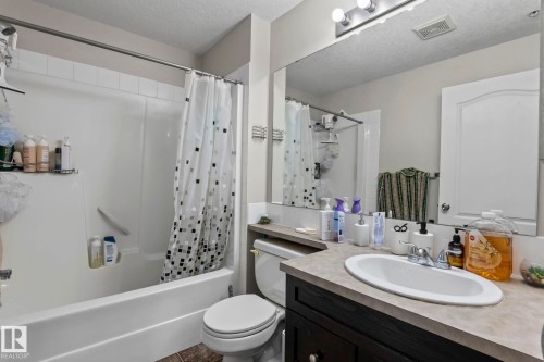 Bathroom featuring a full vanity with an integrated sink, dark wood-finish cabinetry, and a large wall-mounted mirror - 2106 9357 Simpson Dr Nw, Edmonton, AB - Indoor Photo Showing Bathroom