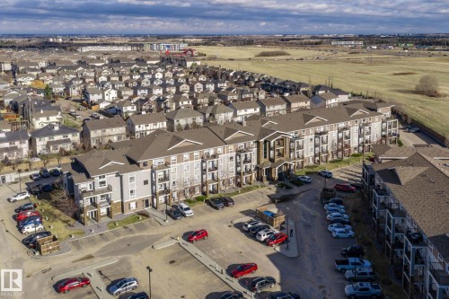 Multi-story residential building featuring a combination of light gray siding, dark brown accents, and stone veneer - 2106 9357 Simpson Dr Nw, Edmonton, AB - Outdoor With View