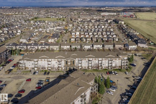 Large multi-story residential building featuring multiple private balconies, a central entrance portico, and a spacious parking area - 2106 9357 Simpson Dr Nw, Edmonton, AB - Outdoor With View