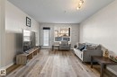 Spacious living area featuring wood-finish flooring, neutral wall tones, a large window, and a white exterior door - 2106 9357 Simpson Dr Nw, Edmonton, AB  - Indoor Photo Showing Living Room 