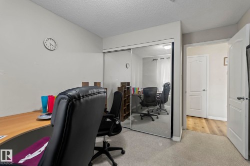 Carpeted interior room featuring mirrored closet doors, a white paneled door, and light-colored walls - 2106 9357 Simpson Dr Nw, Edmonton, AB - Indoor Photo Showing Office
